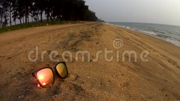 沙滩上的太阳眼镜中的日落反射视频的预览图