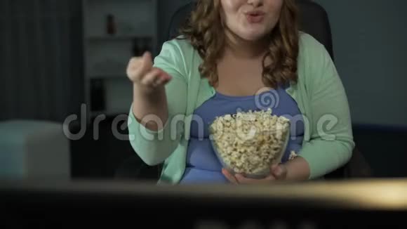 年轻胖女人笑着评论电视节目吃爆米花视频的预览图