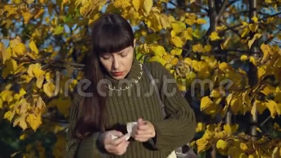 一位穿针织毛衣的年轻女子在黄树背景上的肖像视频的预览图