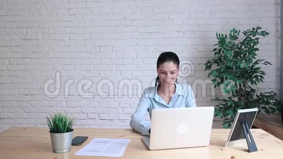 一位女士在办公室的一张桌子上看着时钟在会议上视频的预览图