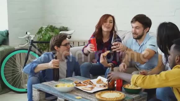 快乐的朋友有聚会聊天和吃披萨他们把瓶子粘在家里的沙发上视频的预览图