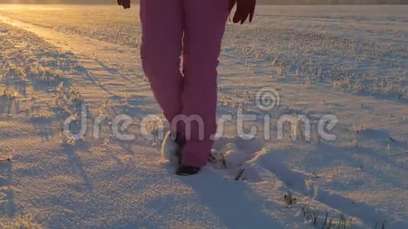 美丽的女人霜冻的冬天在日落的暖流中穿过雪场视频的预览图