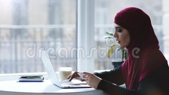漂亮的穆斯林女孩正在笔记本电脑键盘上从名片上输入一些信息印度群岛录像视频的预览图