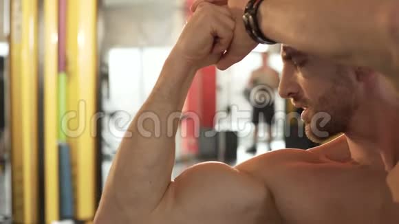 适合男性欣赏他发达的肌肉在健身房做前双头肌姿势视频的预览图