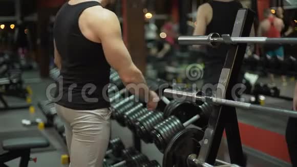 肌肉男交替在健身房举起沉重的哑铃健身视频的预览图