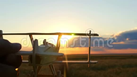 玩具木飞机在日落时在麦田的背景上特写视频的预览图