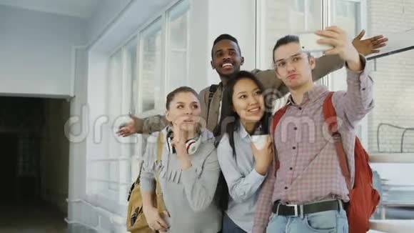 一群多民族的学生在大学走廊里站在智能手机相机上自拍偷鸡仔视频的预览图