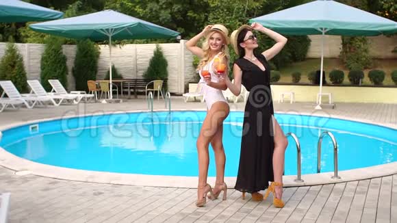 两个女孩站在游泳池附近喝一杯鸡尾视频的预览图