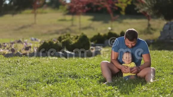 积极的爸爸在草地上玩可爱的小男孩视频的预览图