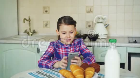 小美丽的女孩在早上玩智能手机而坐在童年人和技术视频的预览图