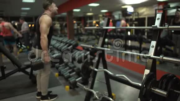 年轻男性在健身房用沉重的哑铃锻炼为完美的身体工作视频的预览图