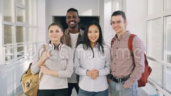 四名积极的多民族男女学生站在大学宽敞的白色走廊上的画像视频的预览图