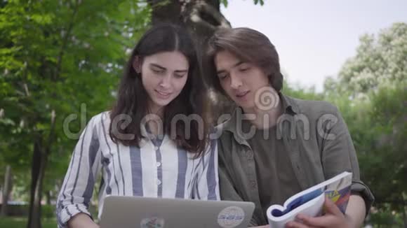男生和女生穿着便服坐在长凳上女生拿着笔记本电脑男生手里拿着日记视频的预览图