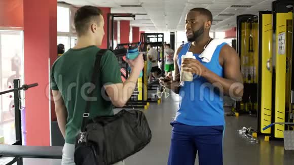 两名运动员在健身俱乐部交谈运动员们喝着蛋白鸡尾酒视频的预览图