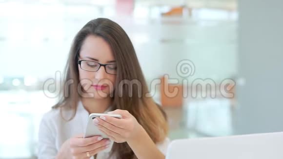 办公室里的商务女孩坐在一张带着笔记本电脑的桌子旁看着电话视频的预览图