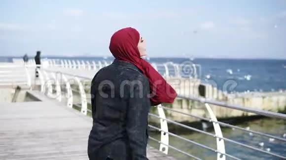 迷人的穆斯林女孩戴着头巾微笑着来回享受着她在海边的散步自由活动视频的预览图