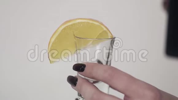 棕色的液体倒在玻璃上柠檬被女人手拿着视频的预览图