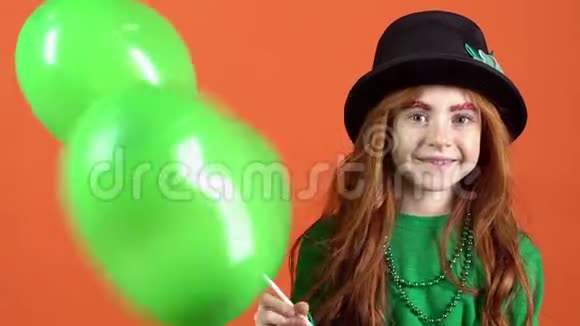 小女孩在橙色的墙上举着气球庆祝圣帕特里克节视频的预览图