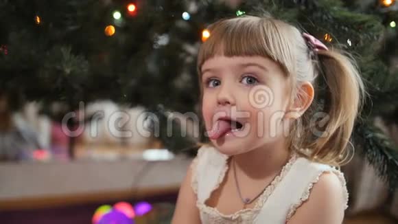 快乐的宝贝女孩鬼脸她脸背景圣诞树视频的预览图