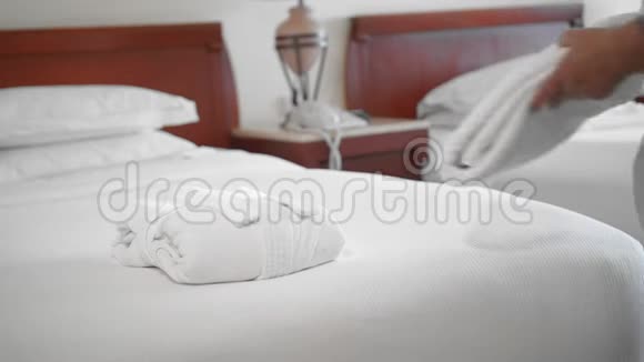 一位未被认出的成年高级妇女把一条白色毛巾放在酒店房间的床上旁边是一件白色浴袍慢动作视频的预览图