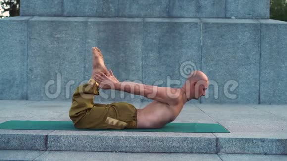 带裸托的年轻瑜伽体式展示了躺在地毯上的瑜伽体式的灵活性视频的预览图