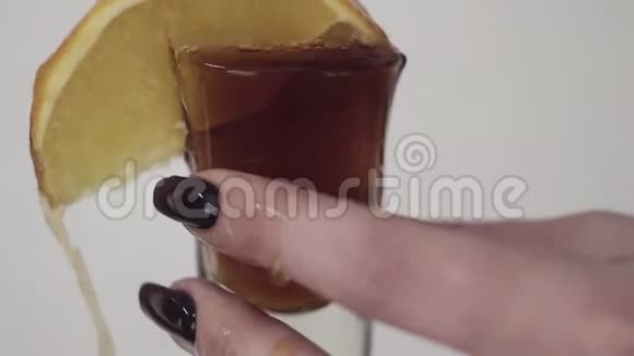 棕色的液体倒在玻璃上柠檬由年轻女子手拿视频的预览图