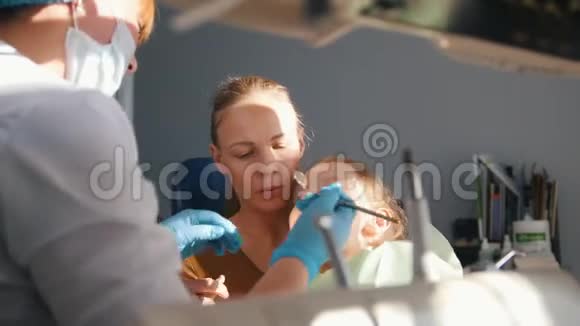 小女孩在接待牙医时口腔医生在给孩子擦牙浇水女孩微笑着视频的预览图