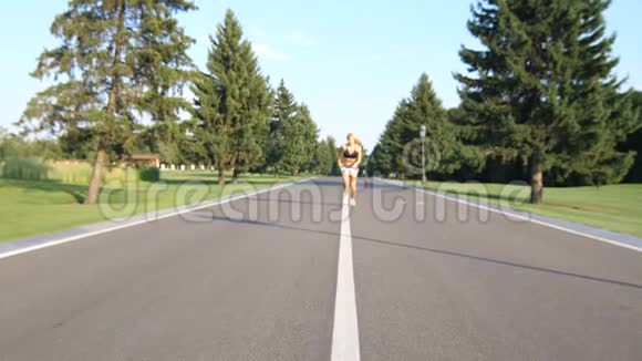 一条美丽健康的金发女郎在夏日阳光下沿着郊区的街道奔跑视频的预览图