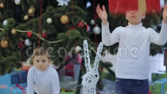 快乐男孩展示新年礼物孩子们站在圣诞树下视频的预览图