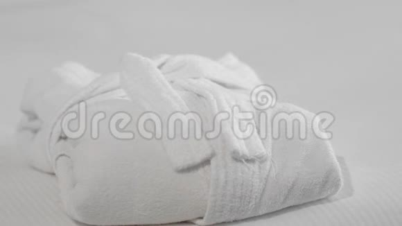 未被识别的成年高级妇女穿着白色浴袍在酒店房间的浴袍旁边的床上放了一条白色毛巾视频的预览图
