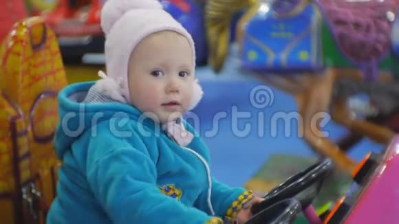 一张15岁的蓝眼睛宝贝玩硬币操作的儿童骑行的肖像小女孩转动玩具车的方向盘视频的预览图