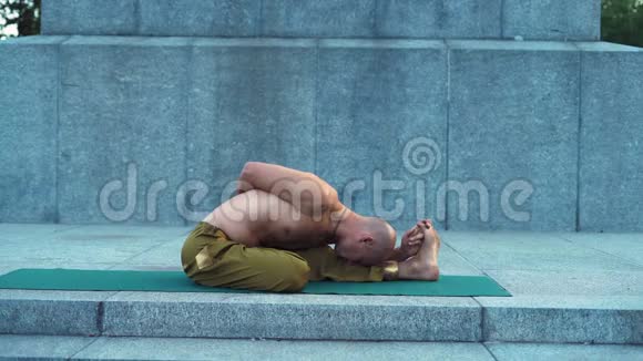 青年男子在花岗岩板上的城市公园完成瑜伽体操视频的预览图