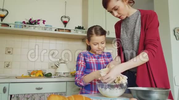 快乐的妈妈和可爱的女儿一起做饭在手里搅拌面团家庭食物家庭和人视频的预览图