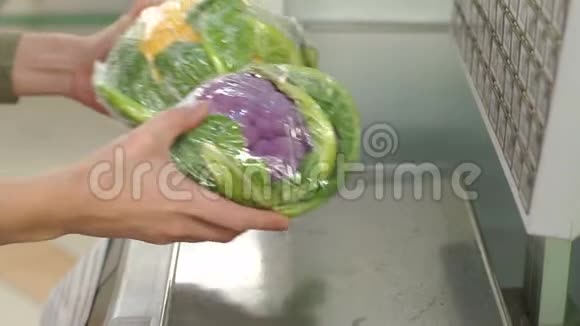 一个在超市里称菜花的女人的特写镜头视频的预览图