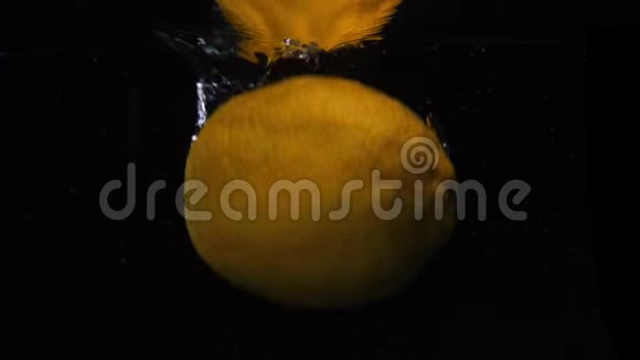 黄色柠檬在黑色背景上掉进水中慢动作宏拍食物视频视频的预览图