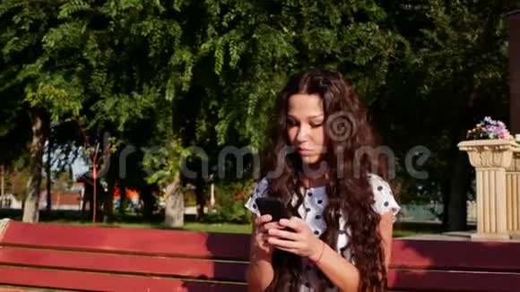 漂亮的白人少女使用智能手机技术应用程序坐在城市的长椅上视频的预览图