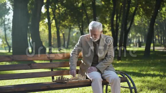 一个有思想的老人独自在公园下棋养老金领取者的社会保障视频的预览图