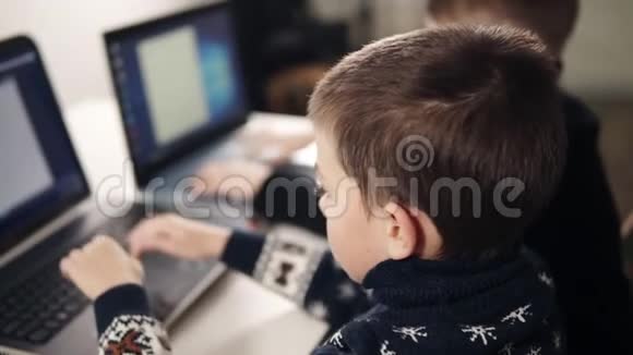 两个男孩学习如何使用笔记本电脑的背面镜头编程课教育过程视频的预览图
