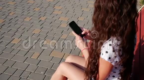 漂亮的白人少女使用智能手机技术应用程序坐在城市的长椅上视频的预览图