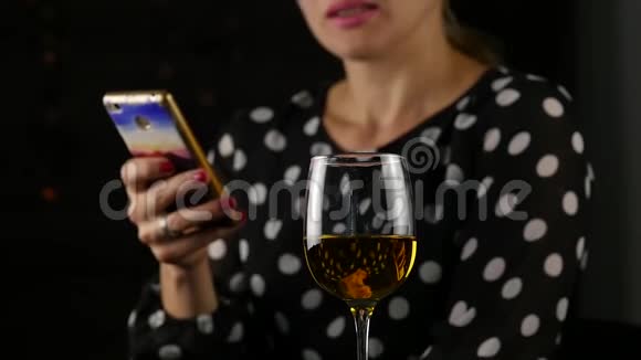 迷人的女人用手机喝白葡萄酒美丽的女士庆祝并发送信息慢动作视频的预览图
