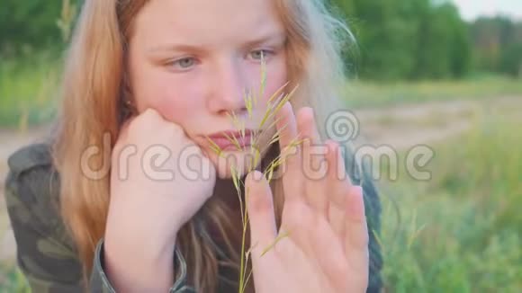 11岁金发少女的肖像又娇又梦幻地看着草叶视频的预览图