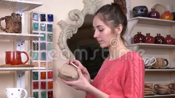 女陶艺师从陶器作坊的各种样品中挑选适合自己杯子的釉色视频的预览图