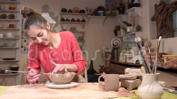 一般的看法一个女孩陶匠平滑粘土锅表面使用流苏在陶器车间视频的预览图