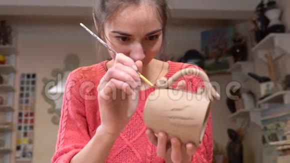快乐女孩陶匠用流苏固定一个生泥杯的表面视频的预览图