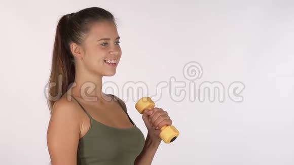 快乐的女运动员带着哑铃在镜头前微笑视频的预览图