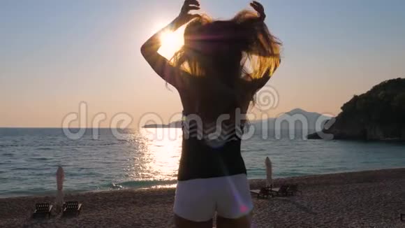 旅游妇女享受海上日落双手伸直头发和飞翔视频的预览图