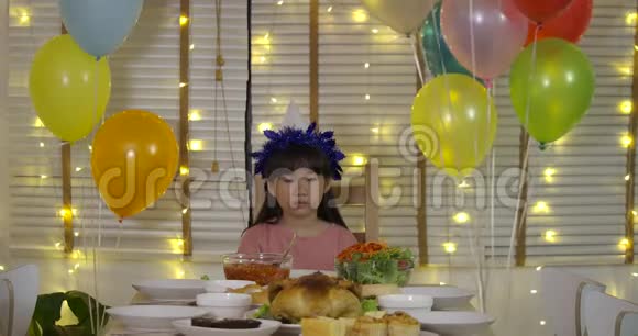 悲伤的亚洲小女孩独自在一张桌子上庆祝她的生日桌子上有一个蛋糕和一支蜡烛动作缓慢视频的预览图