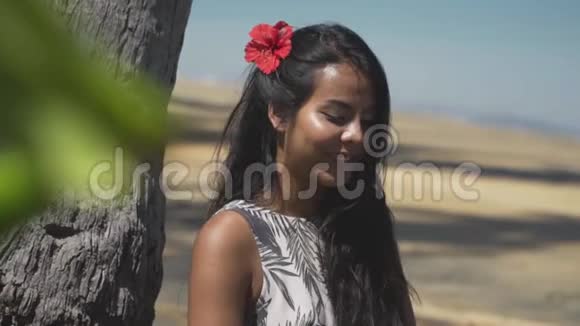 偷窥着一个戴着红花的亚洲女孩在海滩上笑视频的预览图