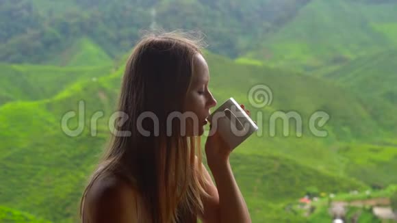 一位年轻女子坐在咖啡馆里观看高地茶台和喝茶的慢镜头视频的预览图