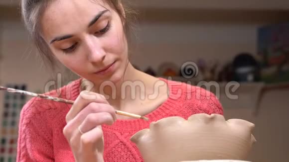 一个女孩陶匠的特写镜头集中在使用流苏平滑粘土锅边视频的预览图